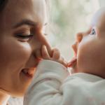 White woman and her baby having a tender moment in front of a window