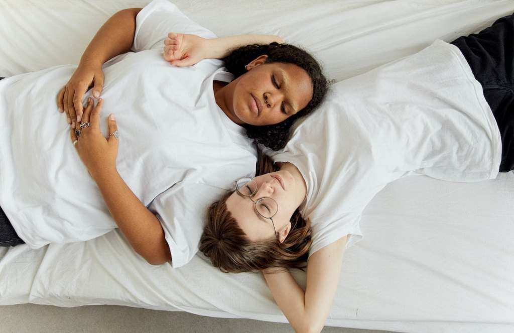 two people laying on bed with arms around each other