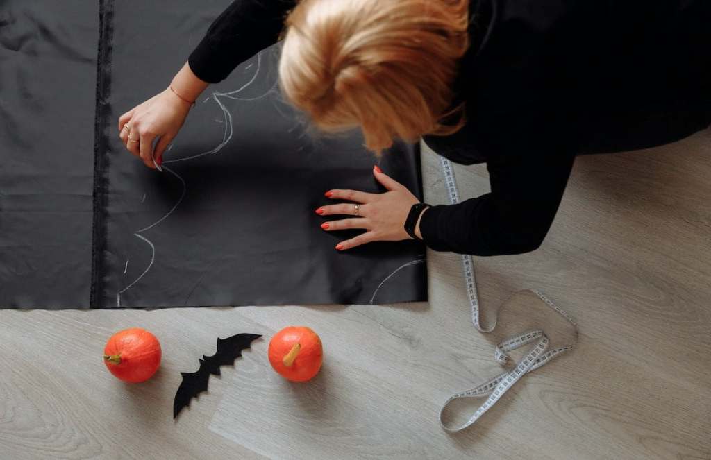 Woman drawing on paper and making halloween decorations