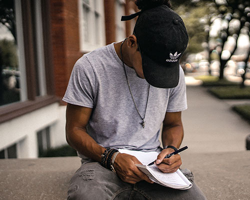 man journaling on sidewalk