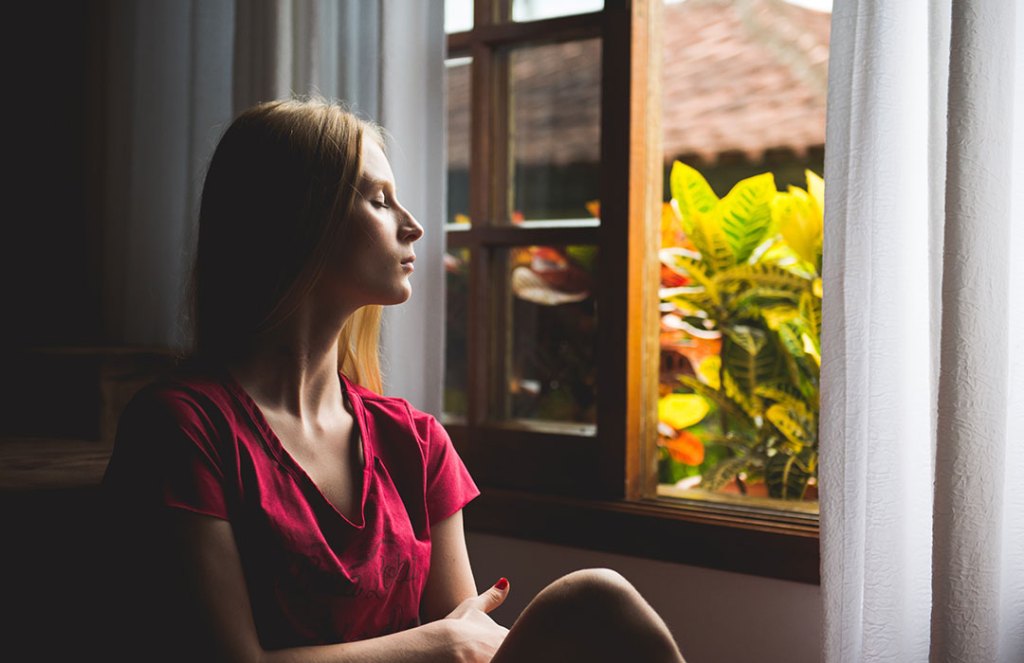 woman looking out of window at plants