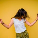 woman dancing in front of yellow wall