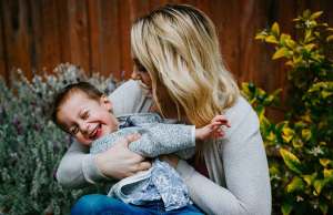 blonde woman in grey sweater holding child in grey shirt