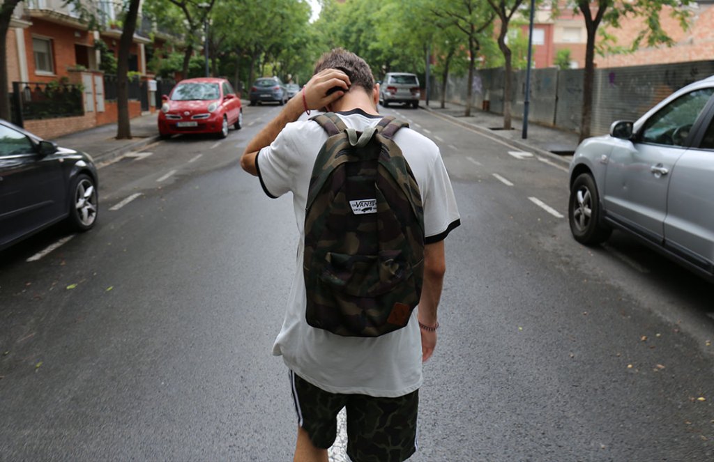teen with backpack walking down street