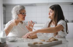 Teen eating cookie while grandma looks surprised