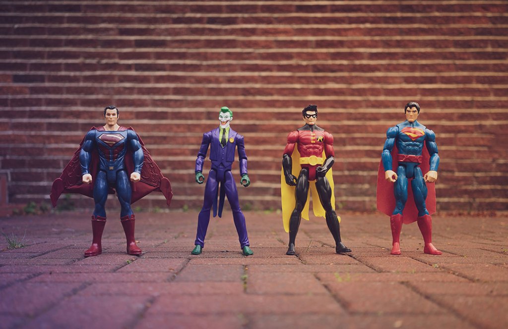4 superhero action figures in front of brick wall