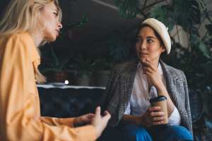 Two women in a coffee shop talking to each other
