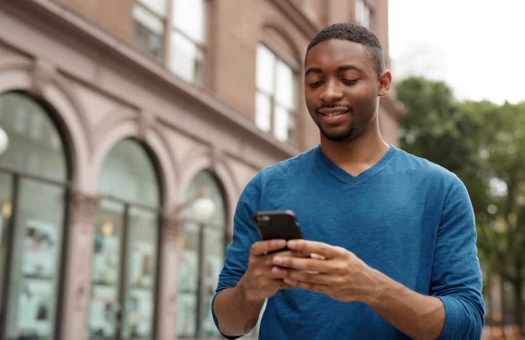 Young urban man using his phone in the city