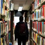 man standing between library books