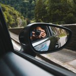 man taking picture in side view mirror