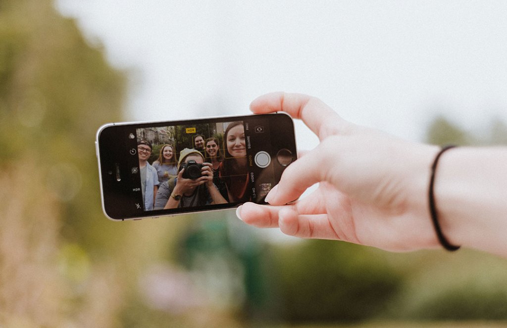 teenagers taking selfie in iphone screen