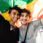 Two queer individuals holding a pride flag