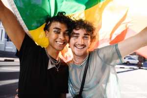 Two queer individuals holding a pride flag