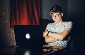man in striped shirt looking at apple laptop