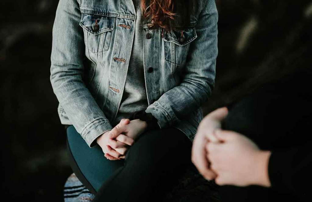 person sitting in denim jacket next to another person sitting in black