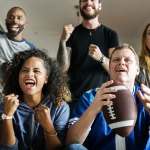 group of men and woman cheering holding a football