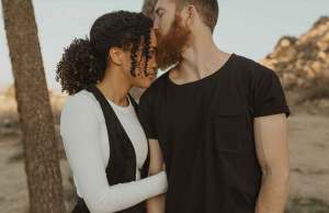 man in black t shirt kissing woman in white shirt and black vest
