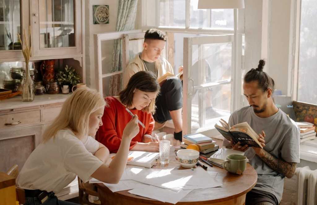 group of friends doing work at a kitchen table