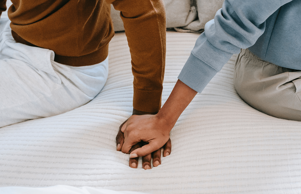 couple holding hands sitting on bed