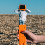 person wearing orange TV helmet with remote in field