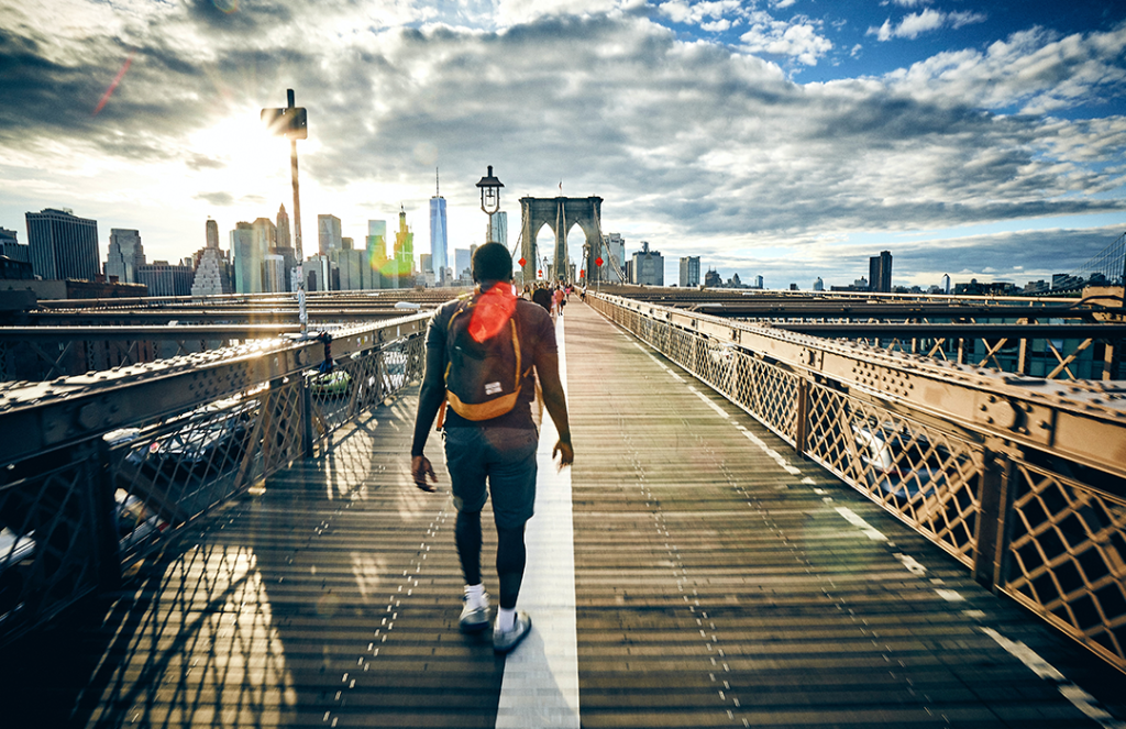 man with backpack walking on bridge in New York City