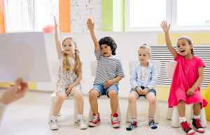 children raising their hands in classroom
