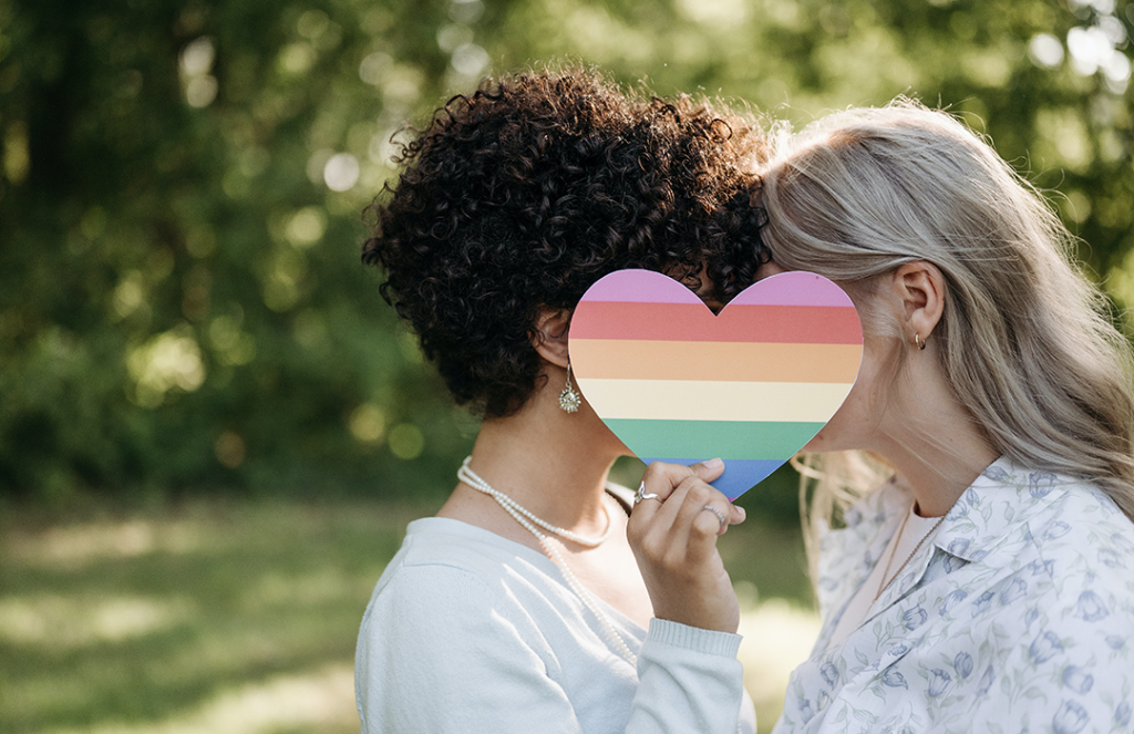 couple kissing behind rainbow heart