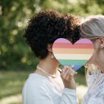couple kissing behind rainbow heart
