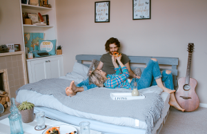 man and woman lying on bed eating pizza