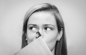 black and white photo of woman covering mouth with file folder
