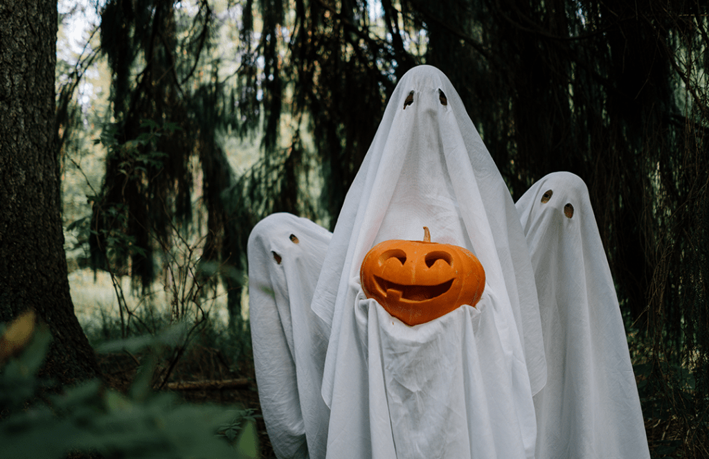 three ghosts holding carved pumpkin