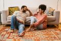 Couple sitting on an orange rug talking and smiling
