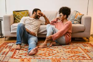 Couple sitting on an orange rug talking and smiling