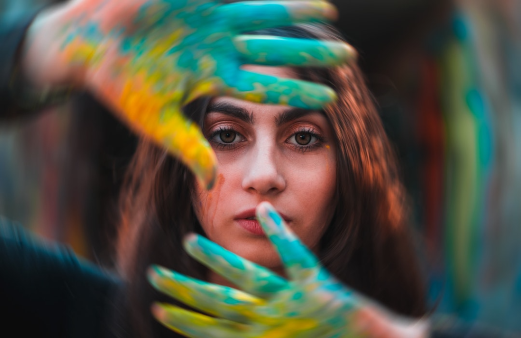 Female artist holds up her colorfully painted hands