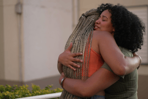 two black women in their 30s hugging