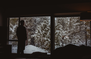 Man staring out large window on snowy day
