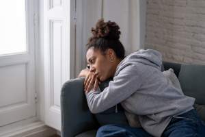 Thoughtful woman laying on a gray couch