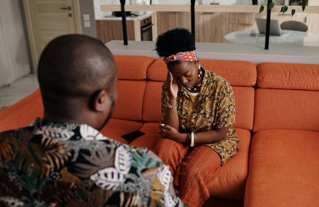 Man and woman communicate intensely on orange couch