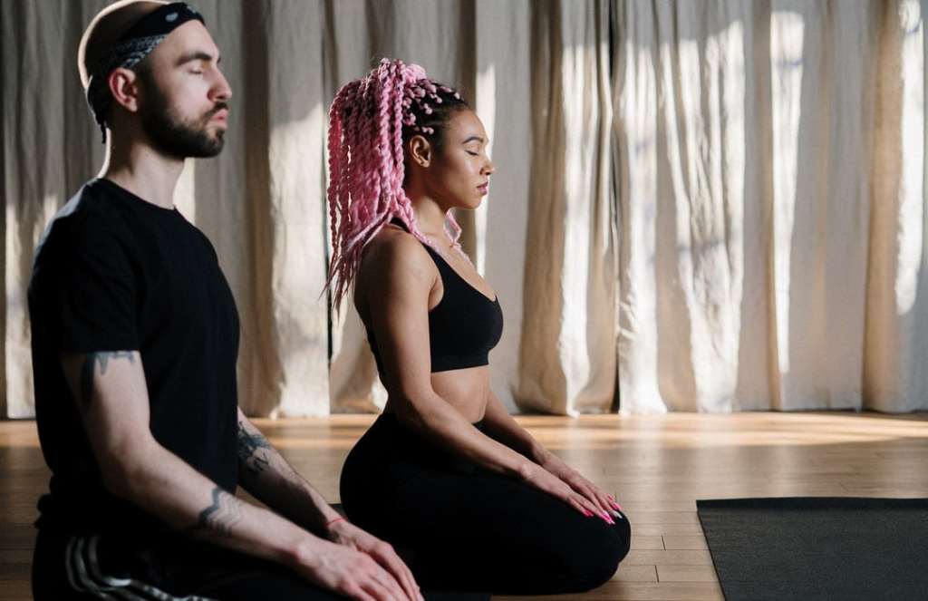 Hip couple meditating in a studio