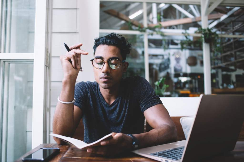 Man journaling at a table with his laptop