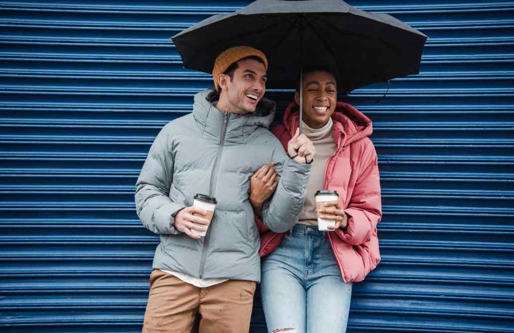 Happy couple drinks coffee under umbrella