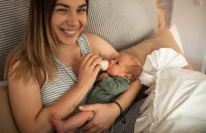 Happy mom bottle feeds newborn infant