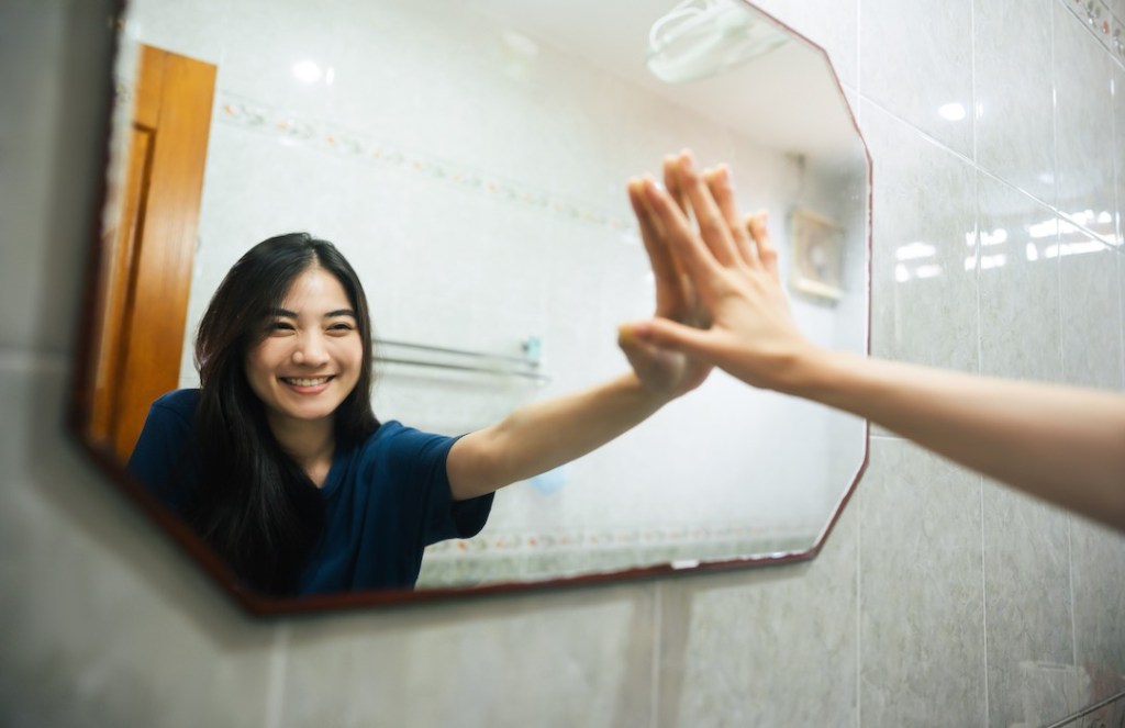 Young adult Asian woman practicing self talk in the mirror