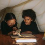 Two cute kids read under a tent--not scared of the dark