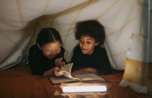 Two cute kids read under a tent--not scared of the dark