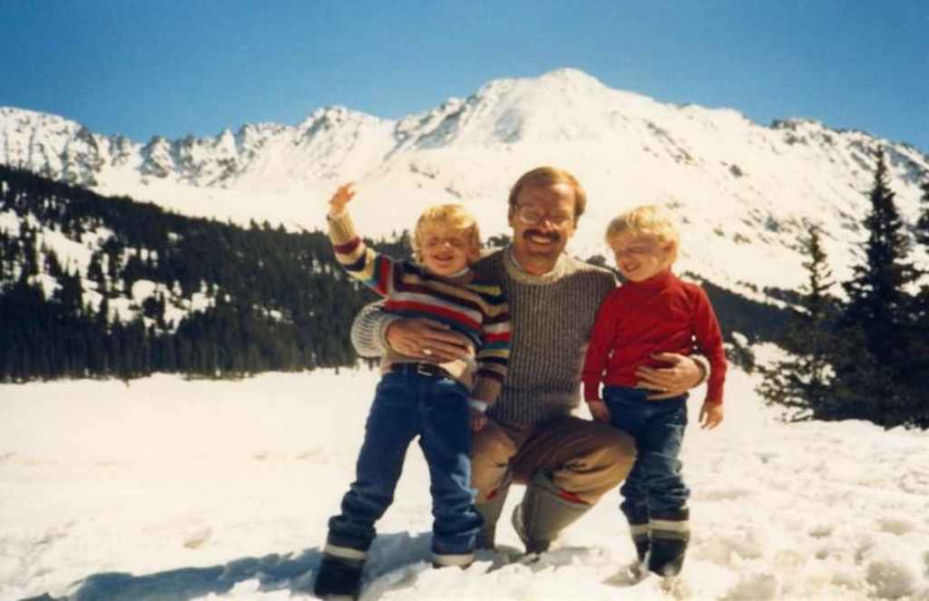 Two kids with adult in front of mountain
