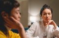 thoughtful-young-ethnic-women-having-conversation-at-table-at-home