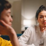 thoughtful-young-ethnic-women-having-conversation-at-table-at-home