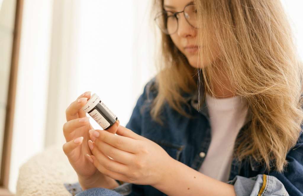 Woman in glasses stares at prescription medication bottle