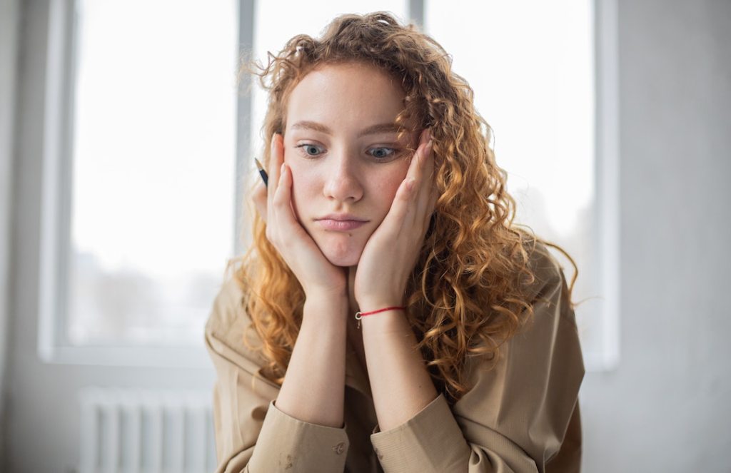 puzzled woman with pen studying in room